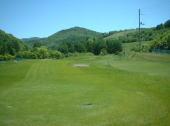 きれいな芝と遠くに山が見えるゴルフ場の写真